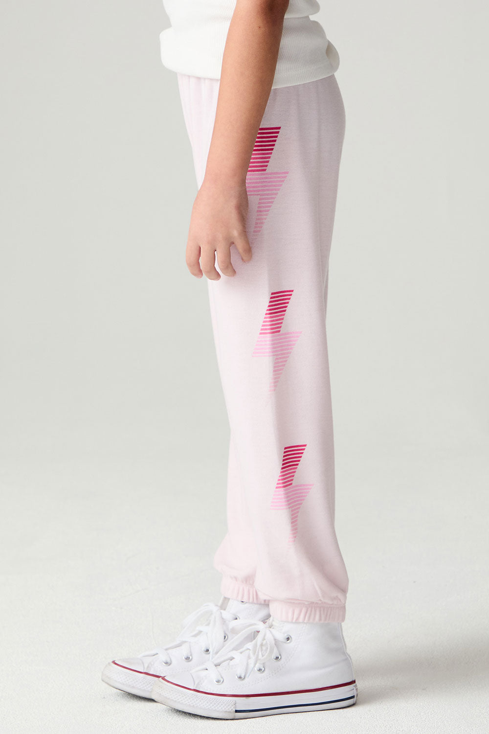 Side view of a girl wearing the Chaser Power Bolt Girls Jogger and sneakers on a neutral background
