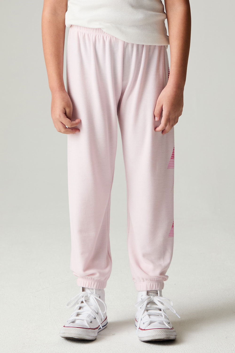 Side view of a girl wearing the Chaser Power Bolt Girls Jogger and white sneakers on a neutral background