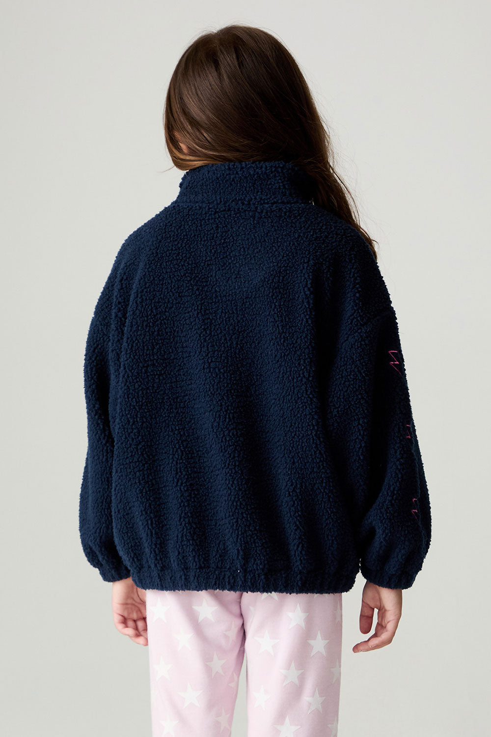 Back view of a girl wearing the Chaser Power Love Girls Jacket on a neutral background with arms down