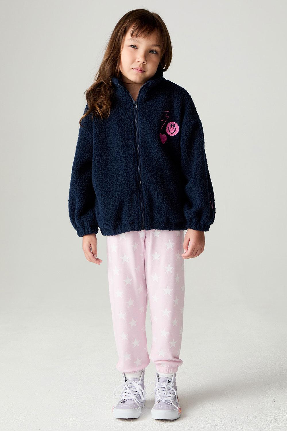 A full body front view of a girl wearing the Chaser Power Love Girls Jacket on a neutral background with pants