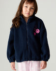 Front view of a girl wearing the Chaser Power Love Girls Jacket on a neutral background with arms down and pink pants