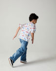 Front view of a boy wearing the Chaser Race Day Boys Tee on a neutral background with bluejeans in a racing pose