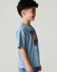 Side view of a boy wearing the Chaser Racers Boys Tee on a neutral background with jeans and arms at sides