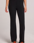 A full body front view of a woman wearing the Chaser Rhose Black Pants on a neutral background with arms at sides