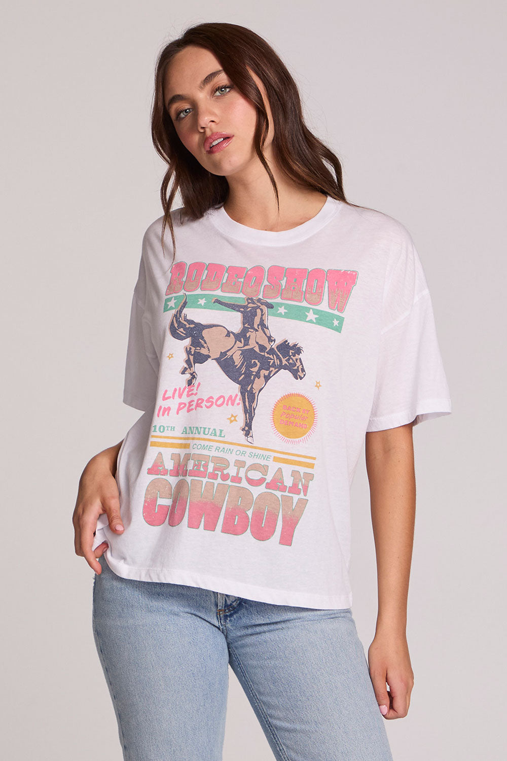 Front view of a woman wearing the Chaser Rodeo Show Tee on a neutral background with pants and hand on hip