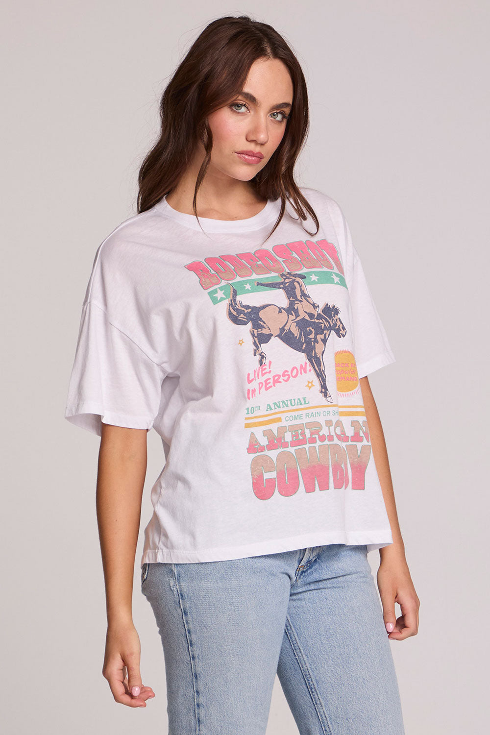 Side angle view of a woman wearing the Chaser Rodeo Show Tee on a neutral background with bluejeans