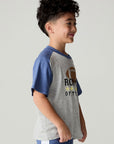 Side view of a boy wearing the Chaser Rookie Boys Tee on a neutral background with arms at sides and blue pants