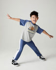 A full body front view of a boy wearing the Chaser Rookie Boys Tee on a neutral background doing a wild pose