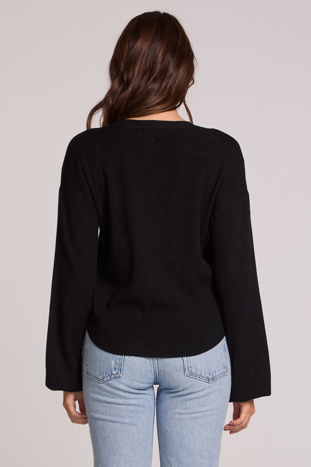 Back view of a woman wearing the Chaser Ruthy Black Fullsleeve Top on a neutral background with jeans