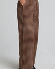 Side view of a woman wearing the Chaser Seren Choco Check Pants on a neutral background with hands in pockets
