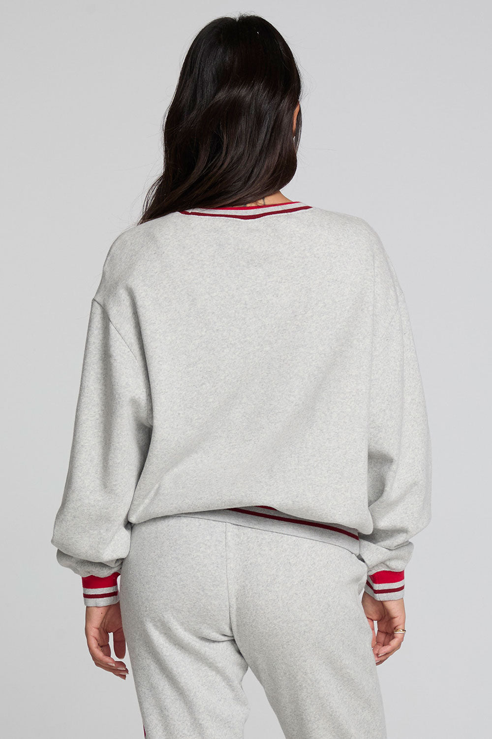 Back view of a woman wearing the Chaser Shocking Bolt Sweatshirt on a neutral background with pants