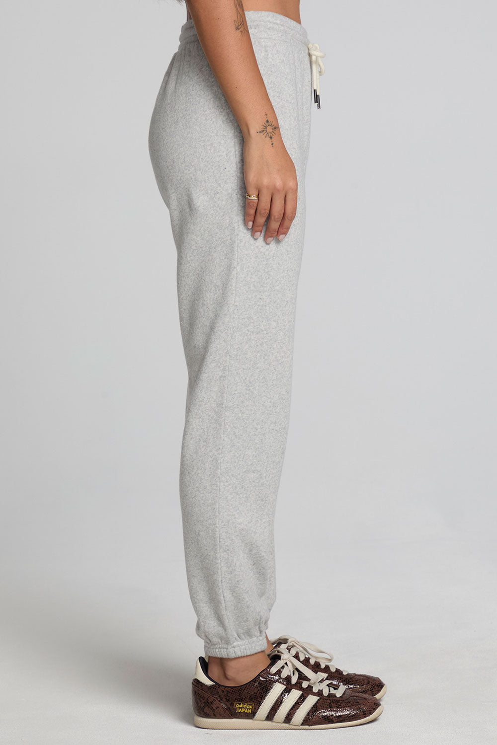 Side view of a woman wearing the Chaser  Shocking Bolt Pants on a neutral background with arms lowered 