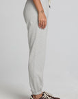 Side view of a woman wearing the Chaser  Shocking Bolt Pants on a neutral background with arms lowered 