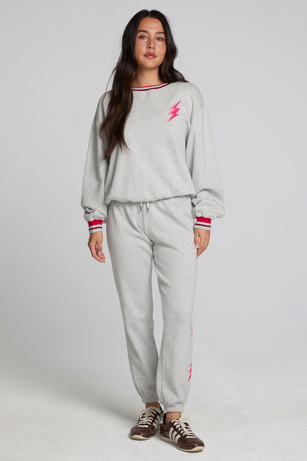 Full body front view of a woman wearing the Chaser  Shocking Bolt Pants on a neutral background with arms lowered at sides and matching long sleeve