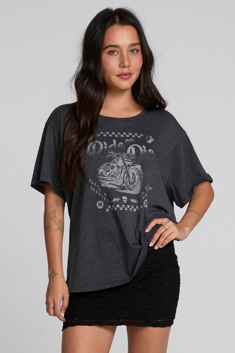 A full body front view of a woman wearing the Chaser Socal Motorcycles Tee on a neutral background with hand on hip