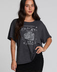 A full body front view of a woman wearing the Chaser Socal Motorcycles Tee on a neutral background with hand on hip