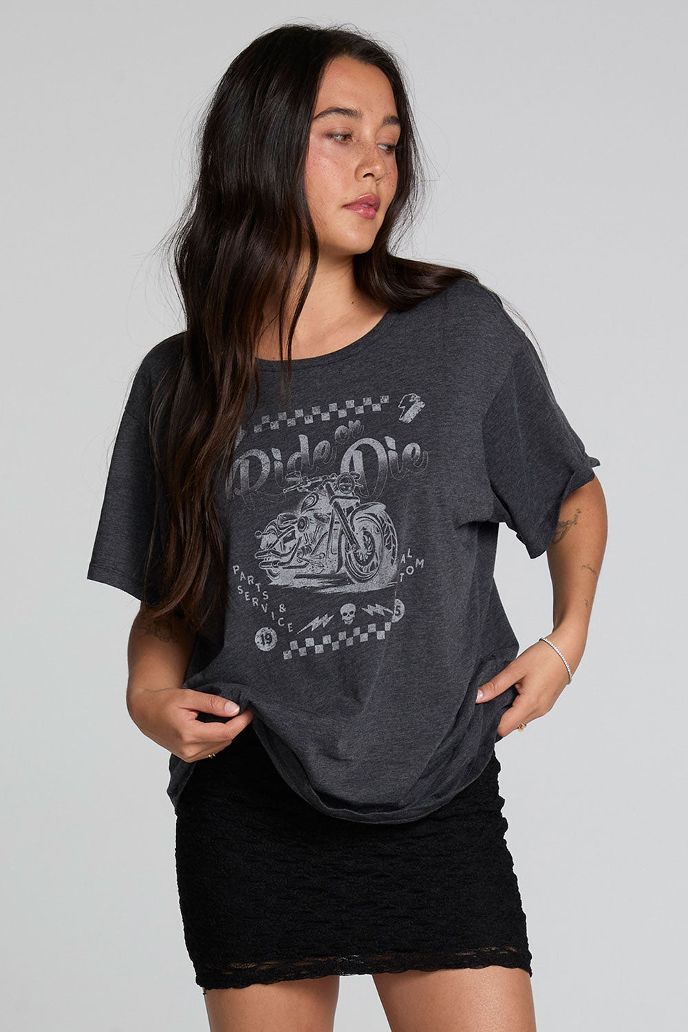 A full body front view of a woman wearing the Chaser Socal Motorcycles Tee on a neutral background with black skirt