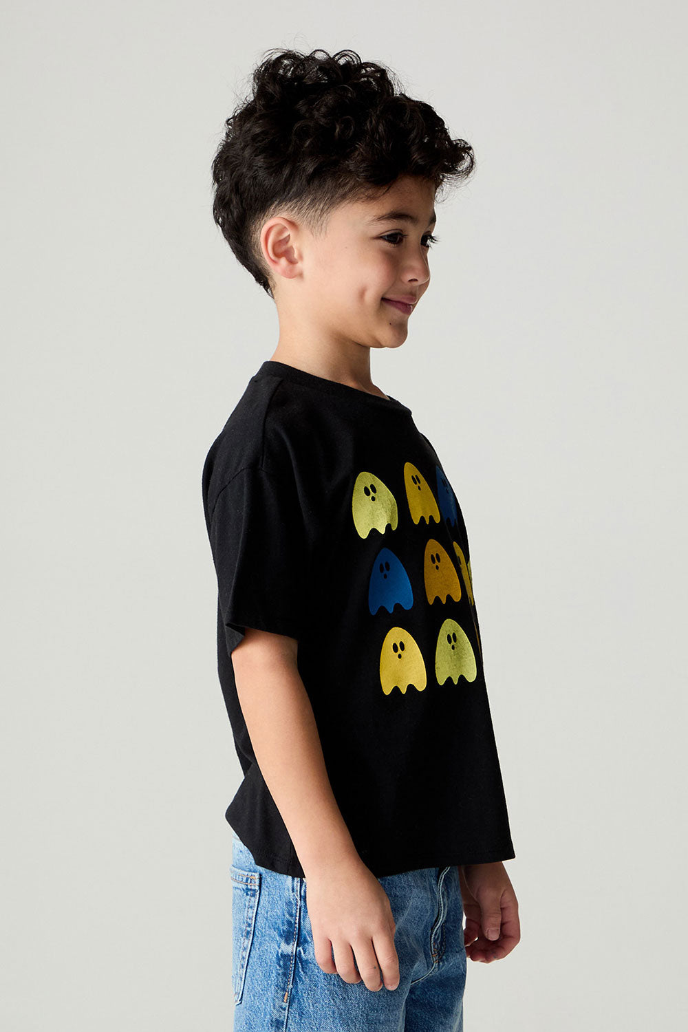 Side view of a boy wearing the Chaser Spooky Friends Boys Tee on a neutral background with bluejeans