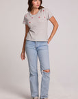 Full body view of a woman wearing the Chaser Star Setter Cropped Tee on a neutral background with ripped blue jeans 