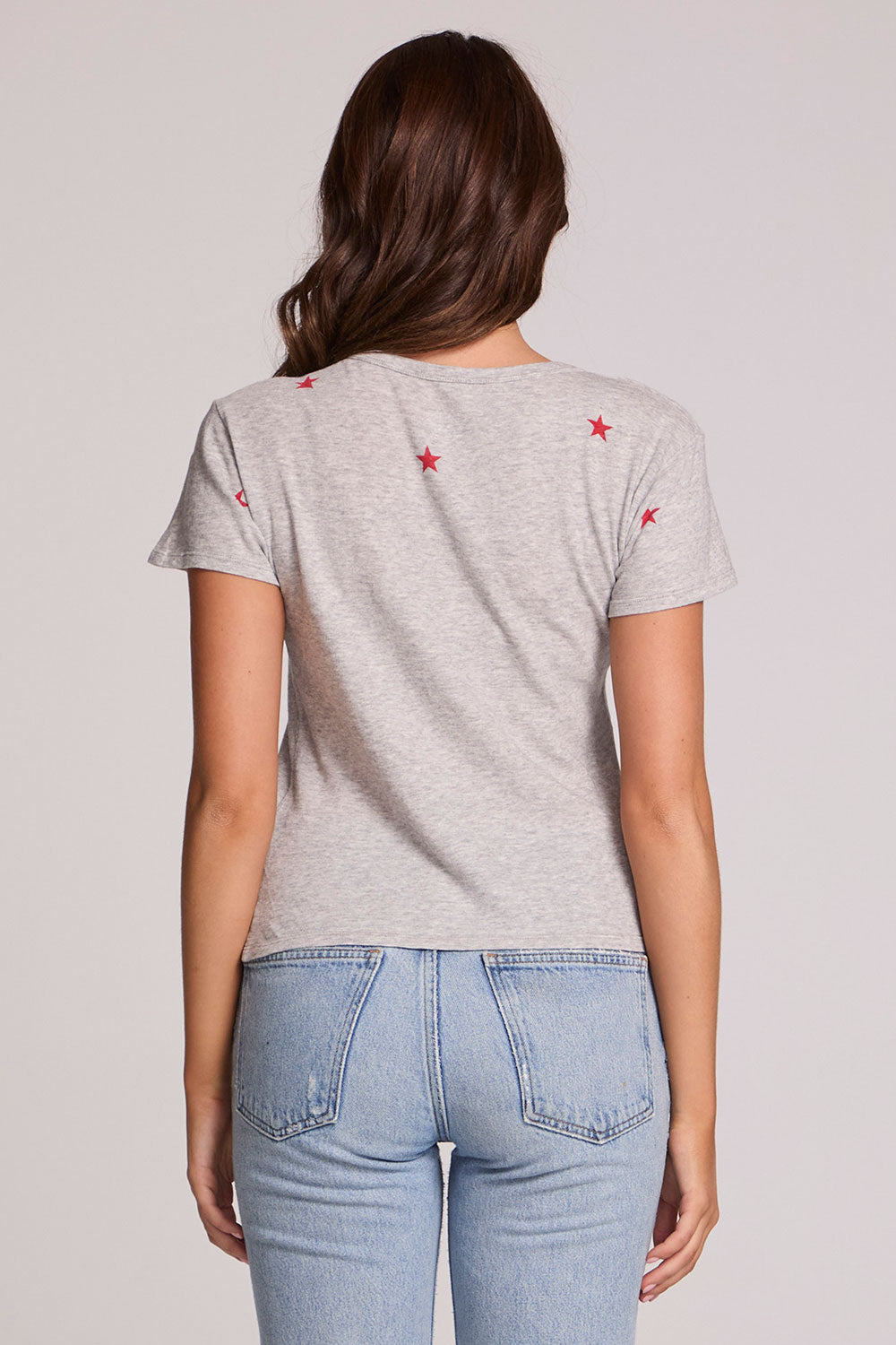 Back view of a woman wearing the Chaser Star Setter Cropped Tee on a neutral background with jeans and hands at sides