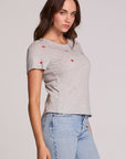 Side angle view of a woman wearing the Chaser Star Setter Cropped Tee on a neutral background with jeans 