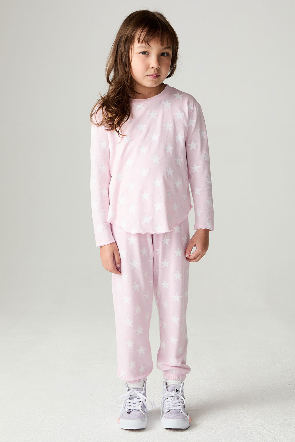 Full body front view of a girl wearing the Chaser Stars Allover Girls Jogger set on a neutral background with arms lowered