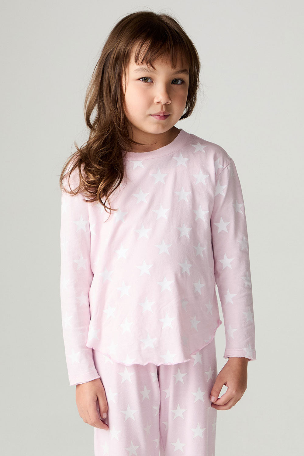 Front view of a girl wearing the Chaser Stars Allover Girls Tee on a neutral background with matching long sleeve top