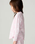 Side view of a girl wearing the Chaser Stars Allover Girls Tee on a neutral background with long sleeve top