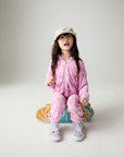 Front view of a girl wearing the Chaser Straight To The Heart Girls Hoodie on a neutral background sitting on a skateboard