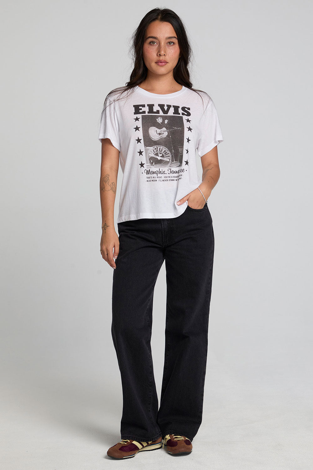 A full body front view of a woman wearing the Chaser Sun Records Elvis 1972 Tee on a neutral background 