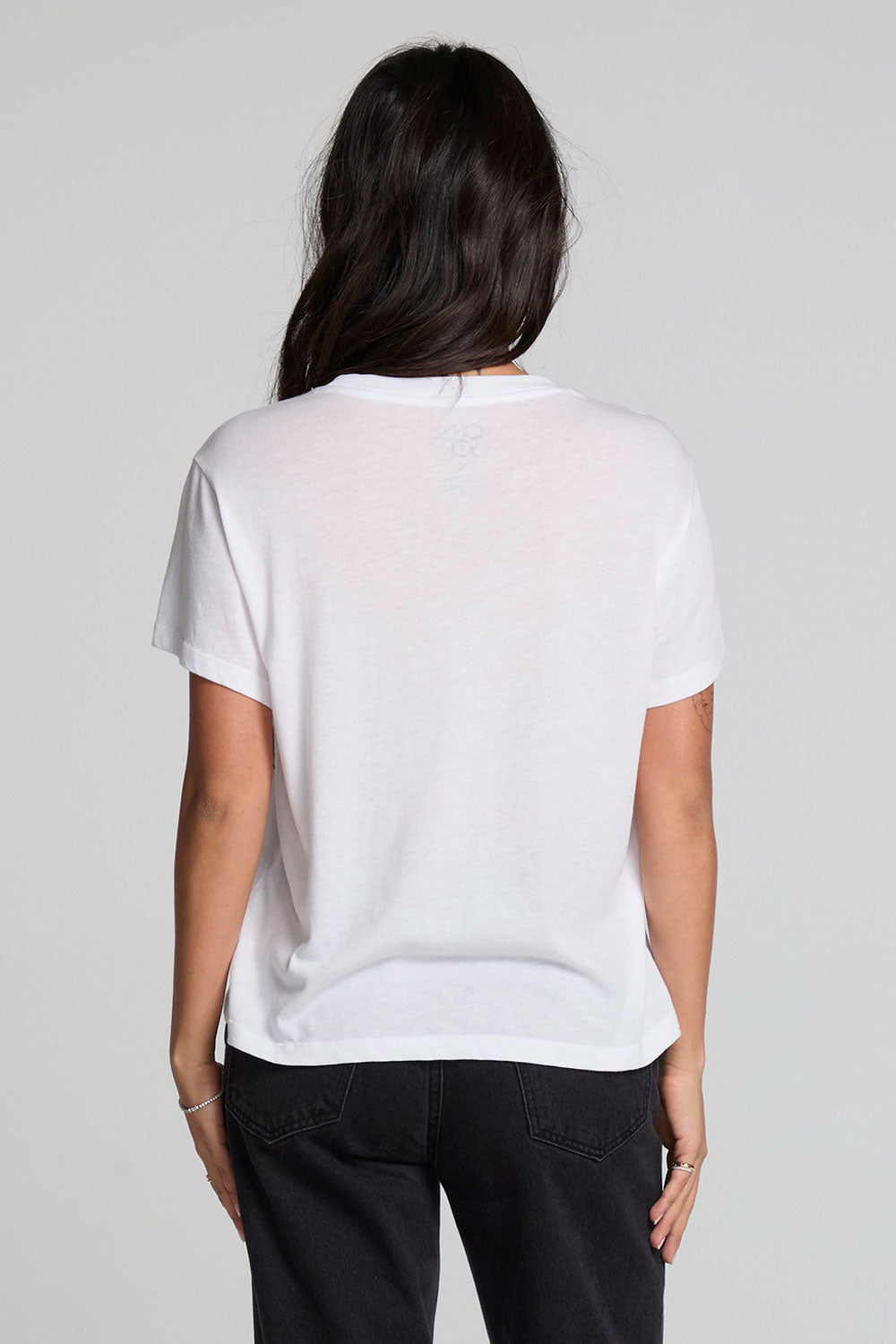 Back view of a woman wearing the Chaser Sun Records Elvis 1972 Tee on a neutral background with arms at sides