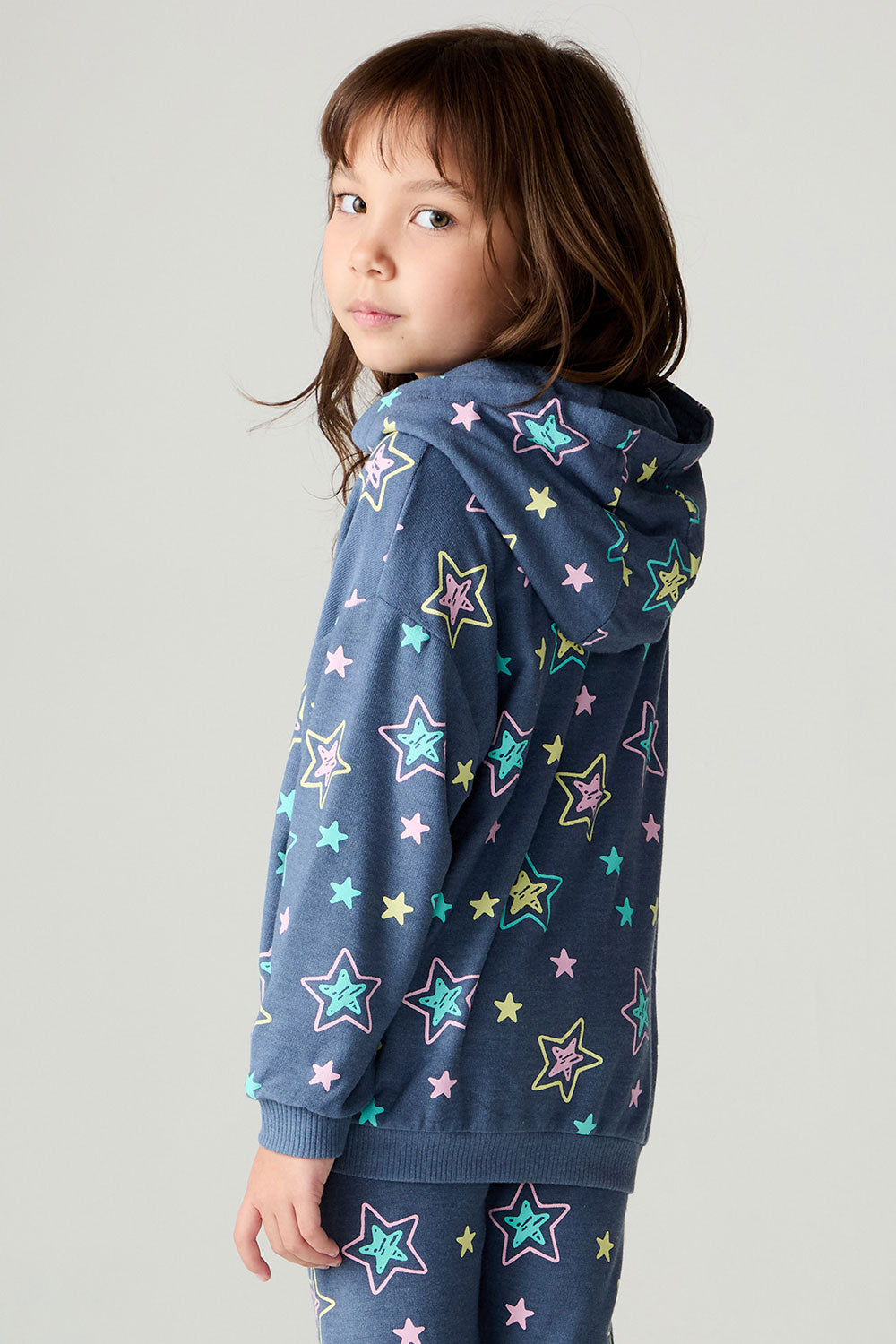 Back view of a girl wearing the Chaser Super Star Girls Zip Up on a neutral background with matching pants