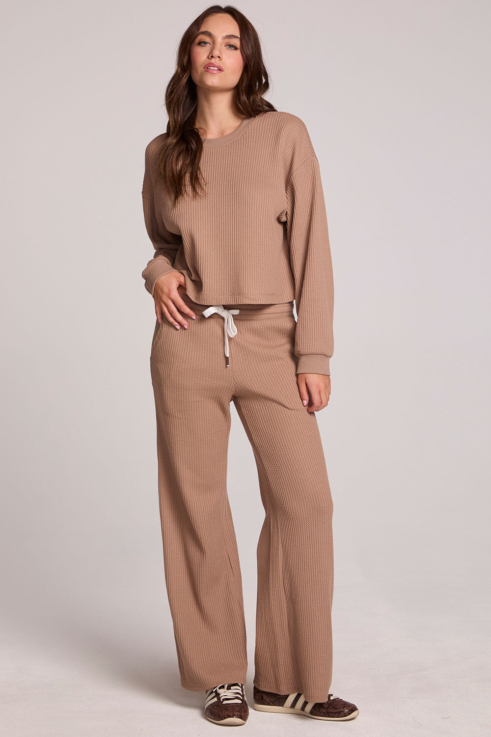 A full body front view of a woman wearing the Chaser Suzzans Camel Cropped Sweatshirt on a neutral background