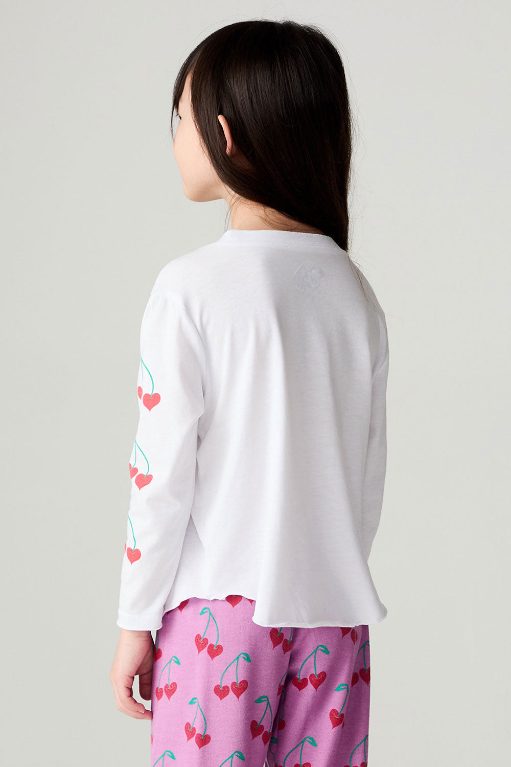 Back view of a girl wearing the Chaser Sweethearts Girls Tee on a neutral background with pants
