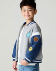 Side view of a boy wearing the Chaser Team Spirit Boys Jacket on a neutral background with jeans and shirt