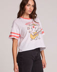 Side angle view of a woman wearing the Chaser Teddy Tee on a neutral background and black pants