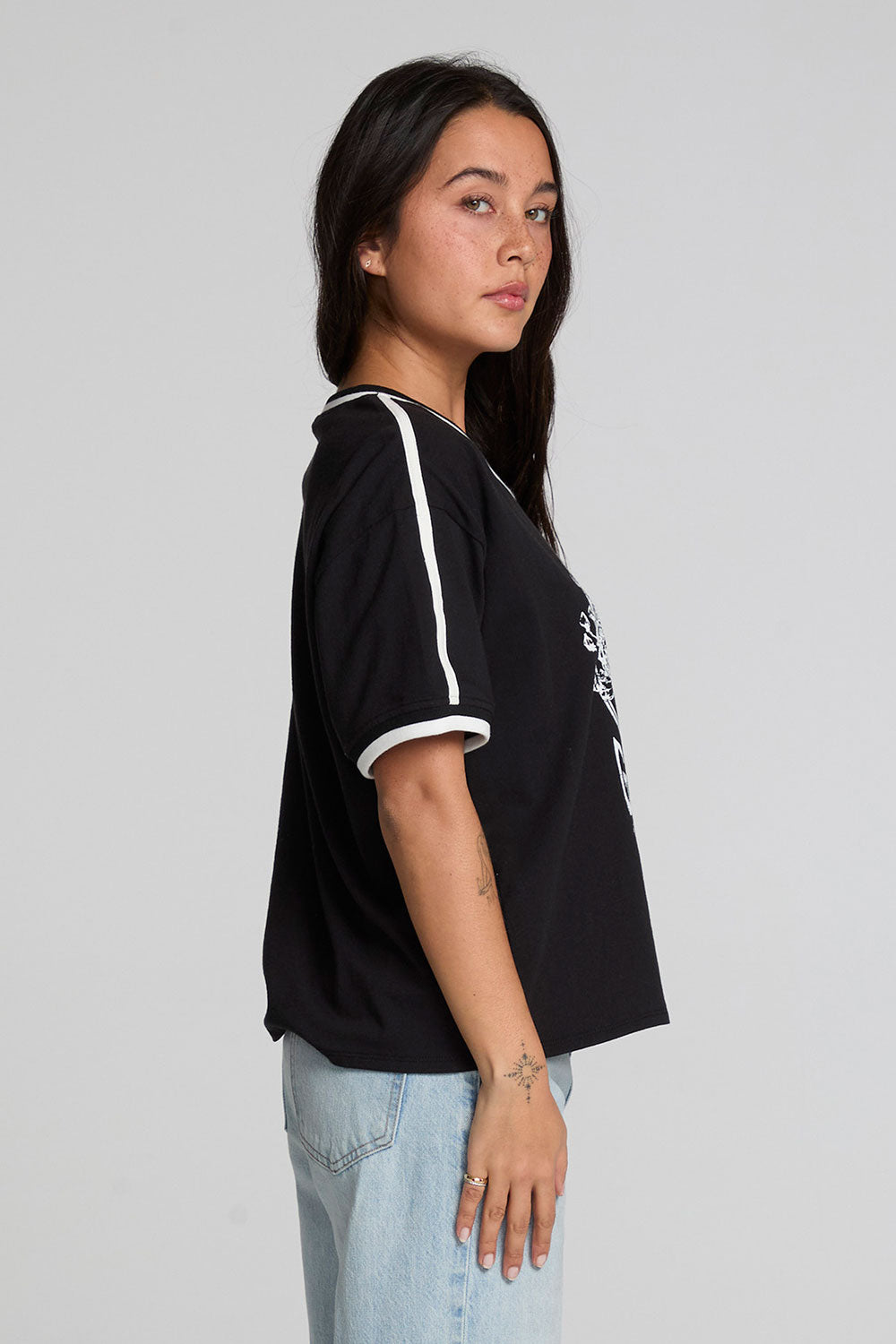 Side view of a woman wearing the Chaser The Grateful Dead Winterland Area Tee on a neutral background with bluejeans