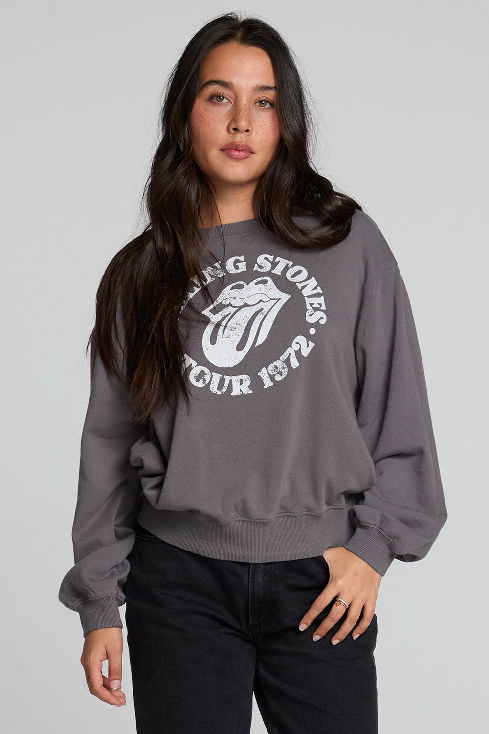 Frontview of a woman wearing the Chaser The Rolling Stones 78 Tour Cropped Sweatshirt on a neutral background with black pants an d hand in pocket