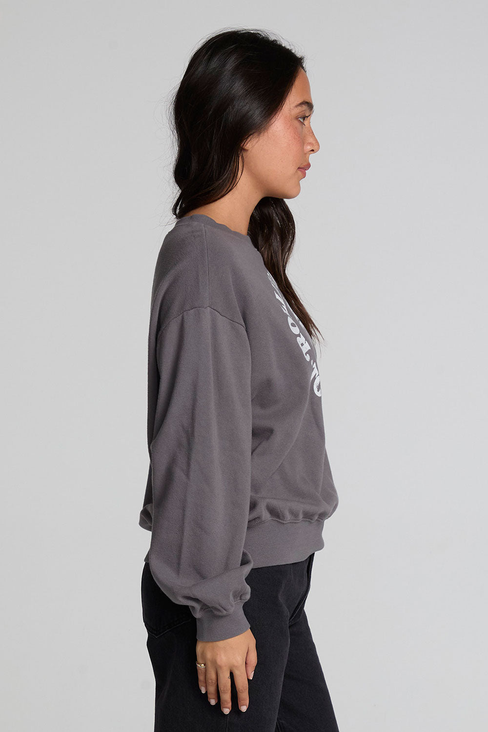 Back view of a woman wearing the Chaser The Rolling Stones 78 Tour Cropped Sweatshirt on a neutral background with black pants