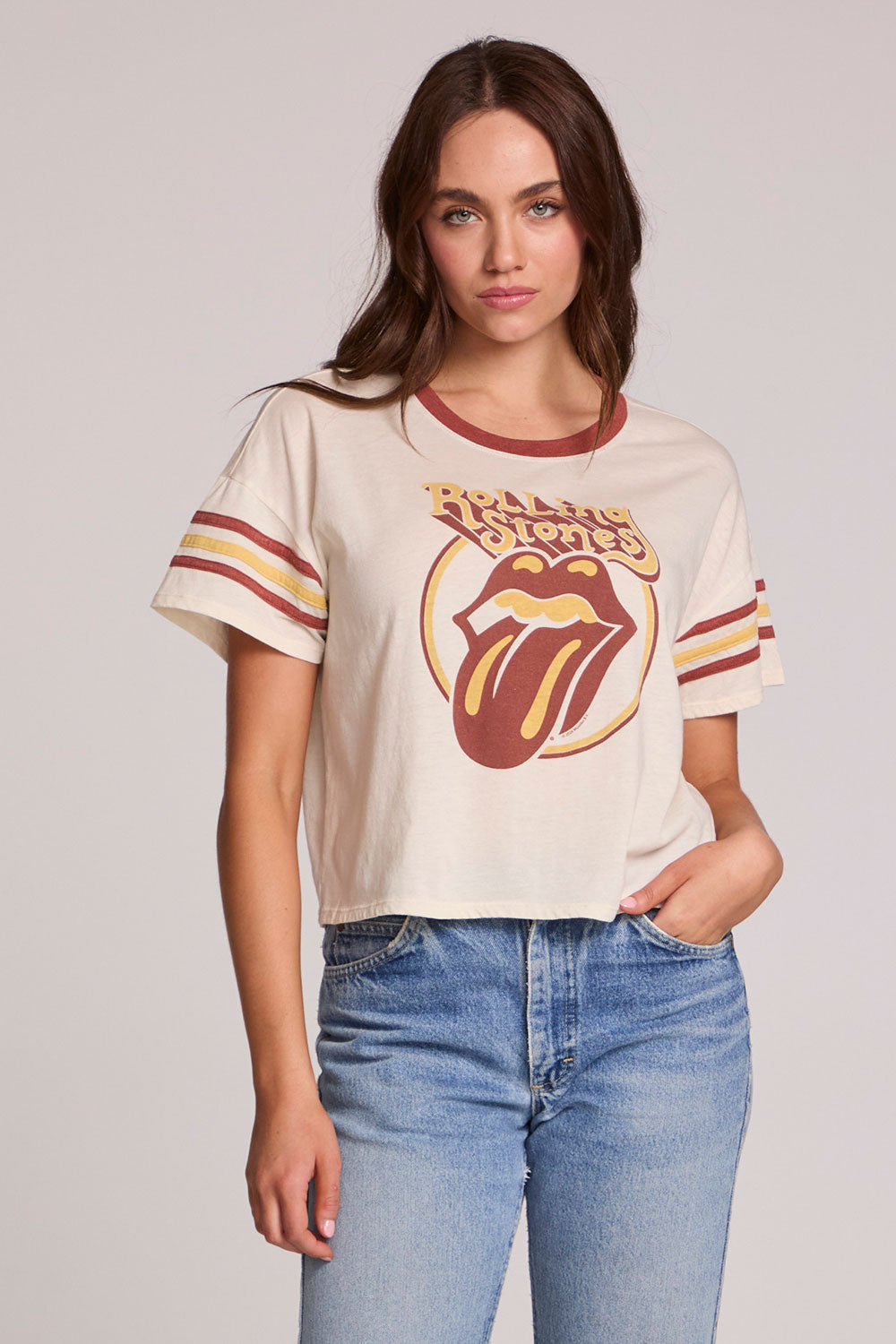 Front view of a woman wearing the Chaser  The Rolling Stones Retro Tongue Tee on a neutral background with jeans and hand in pocket