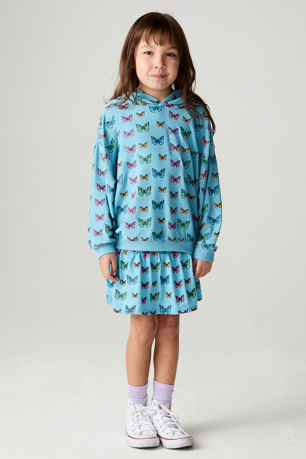 A full body front view of a girl wearing the Chaser Tiny Hearts Skirt Girls Skirt on a neutral background