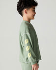 Side view of a boy wearing the Chaser Touchdown Boys Tee on a neutral background with long-sleeve shirt