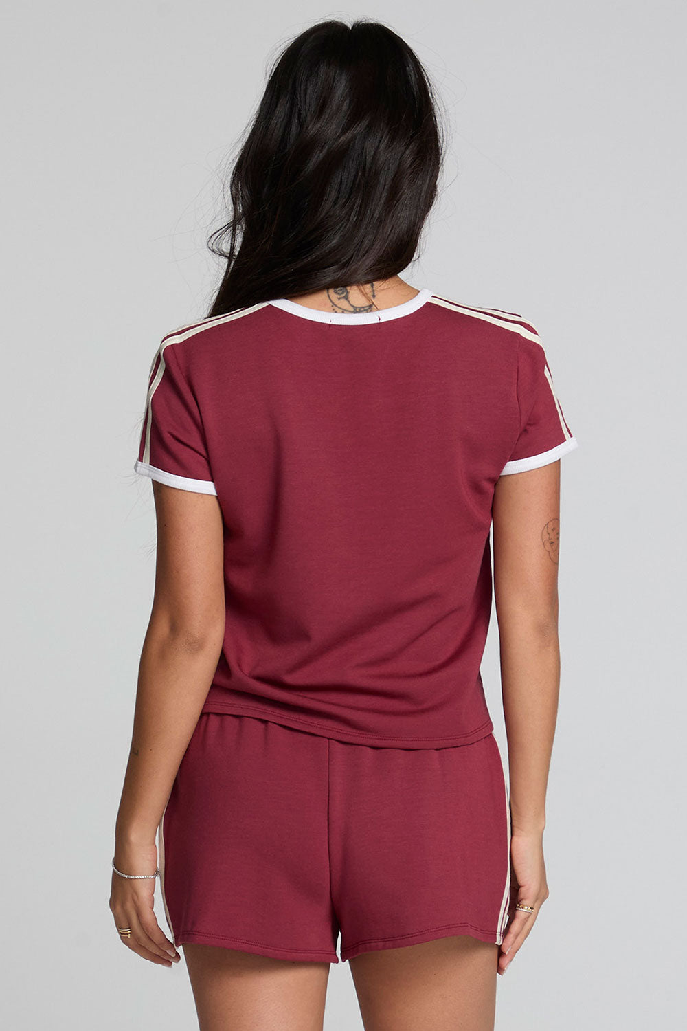 Back view of a woman wearing the Chaser Urban Burnt Red Tee on a neutral background with shorts