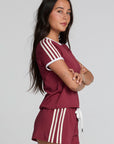 Side view of a woman wearing the Chaser Urban Burnt Red Tee on a neutral background with red shorts