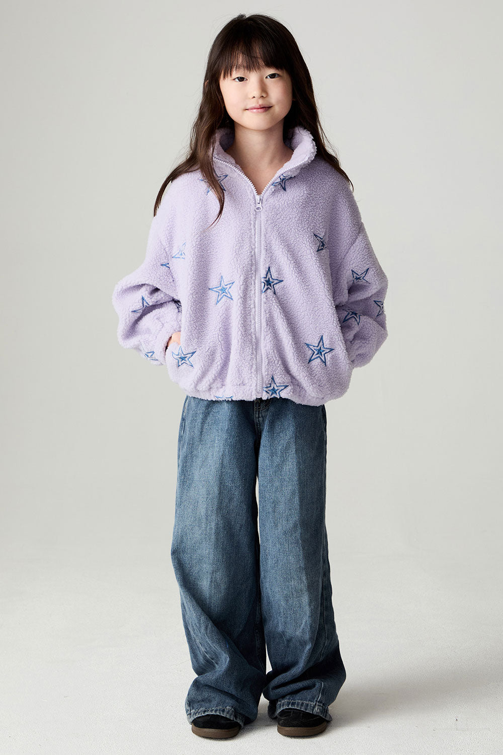 A full body front view of a girl wearing the Chaser Varsity Stars Girls Varsity Jacket on a neutral background