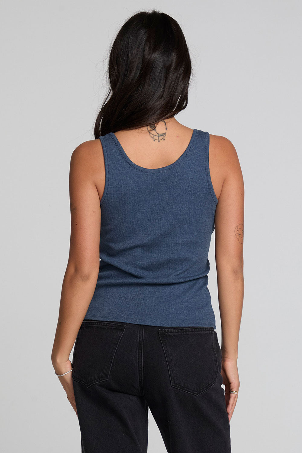 Back view of a woman wearing the Chaser Velora Dark Denim Tank on a neutral background with hands at sides