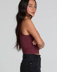 Side view of a woman wearing the Chaser Verze Brick Tank and jeans on a neutral background with arms crossed 