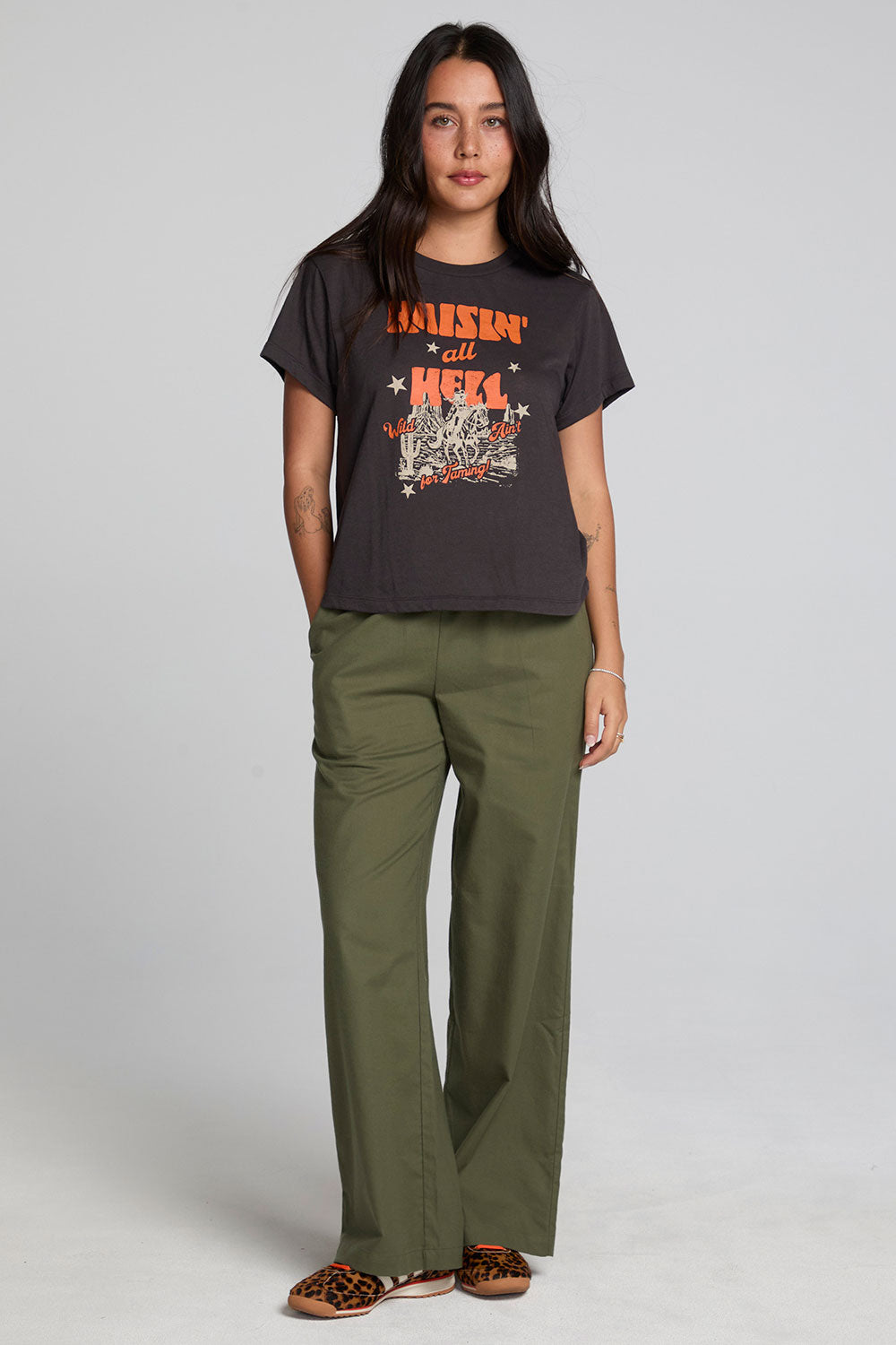 Full body front view of a woman wearing the Chaser  Wild And Free Cropped Graphic Tee on a neutral background