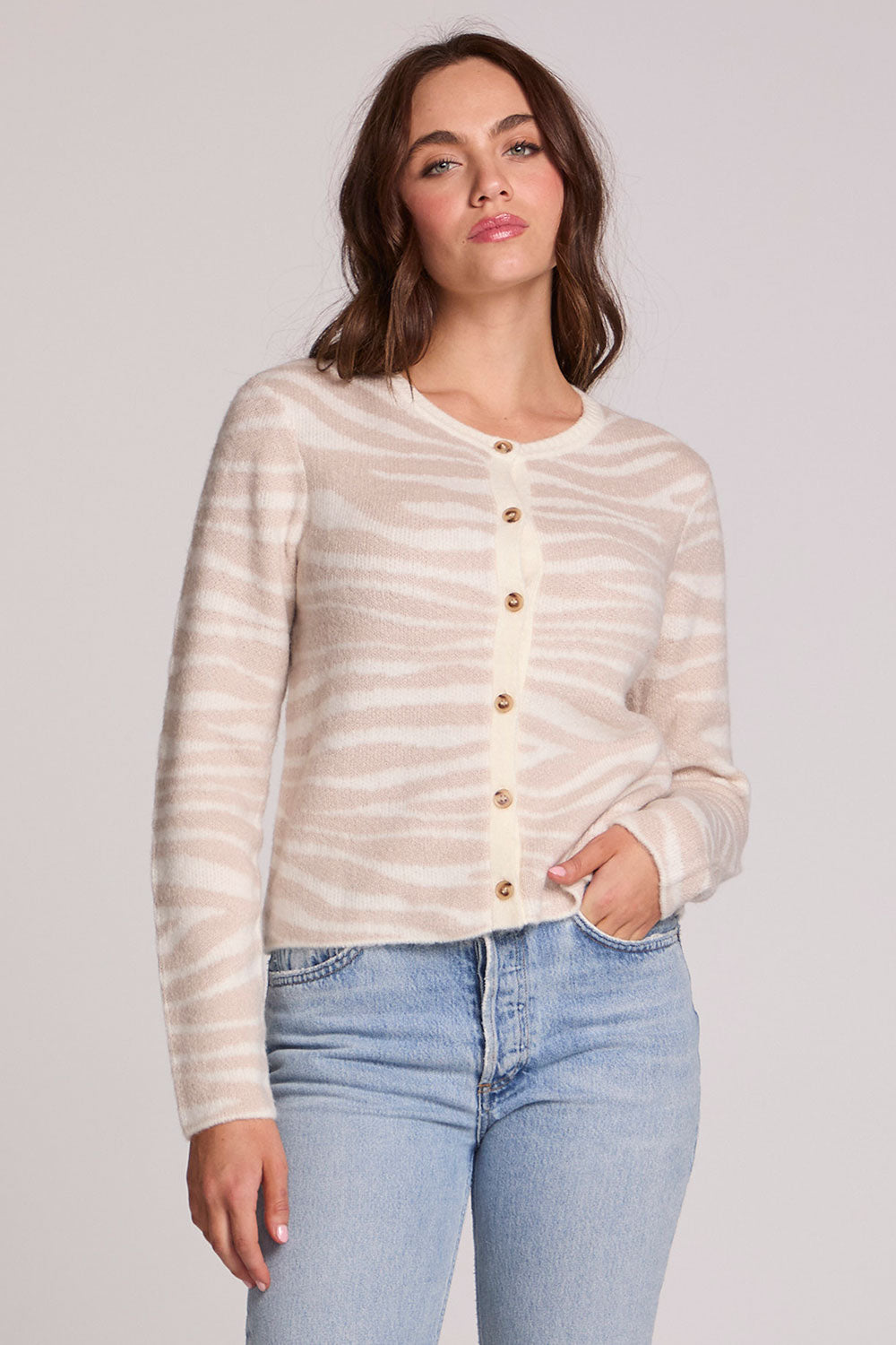 Front view of a woman wearing the Chaser   Zebra Dream Striped Cardigan on a neutral background with one hand in pocket
