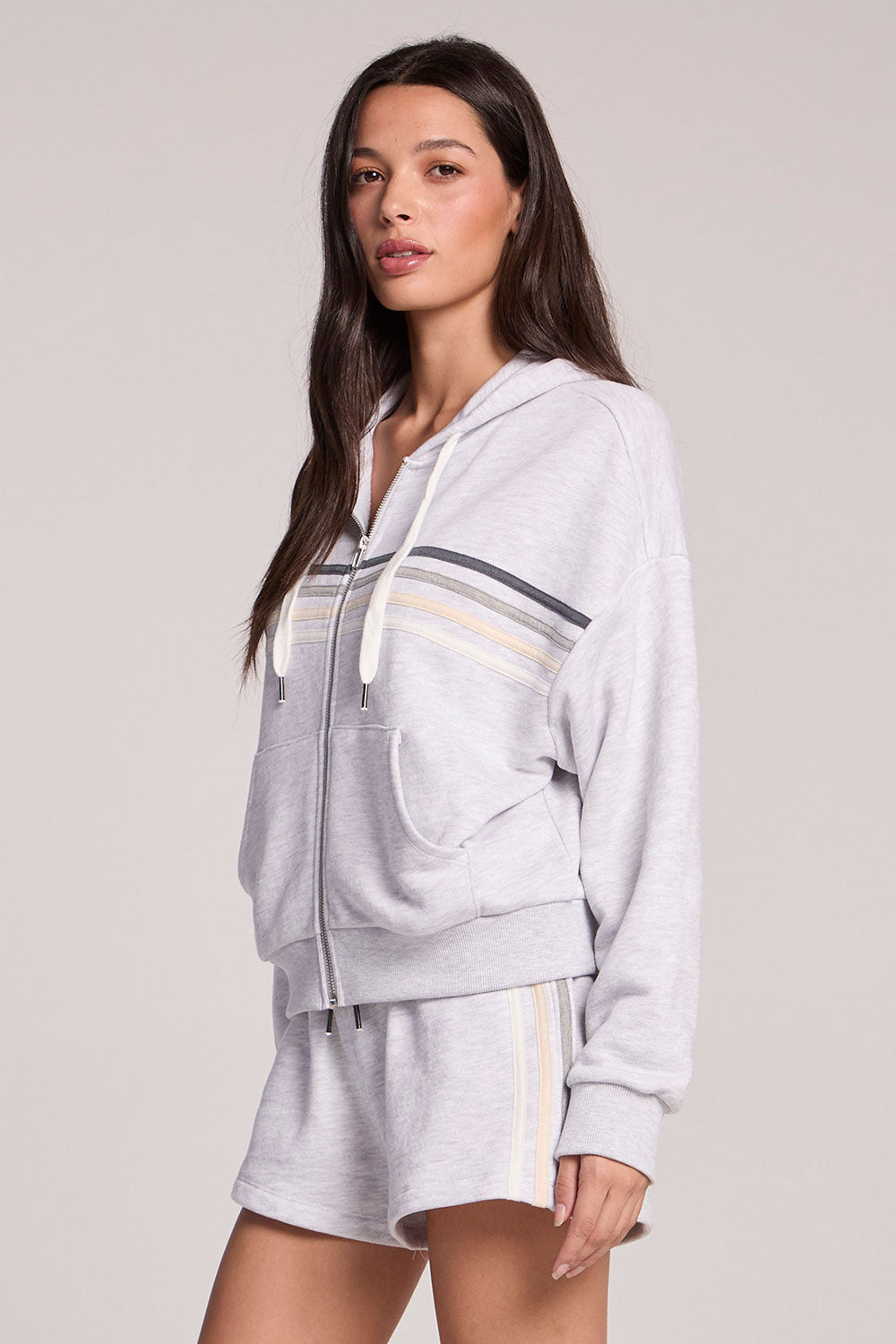 Side angle view of a woman wearing the Chaser Contrast Strappings Zip-Up set on a neutral background